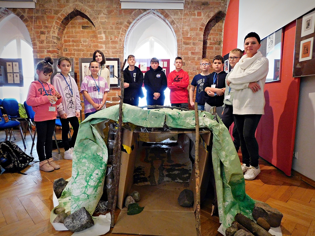 zdjęcie grupowe uczestników AM i wykładowczyni przy imitacji grobu olbrzyma