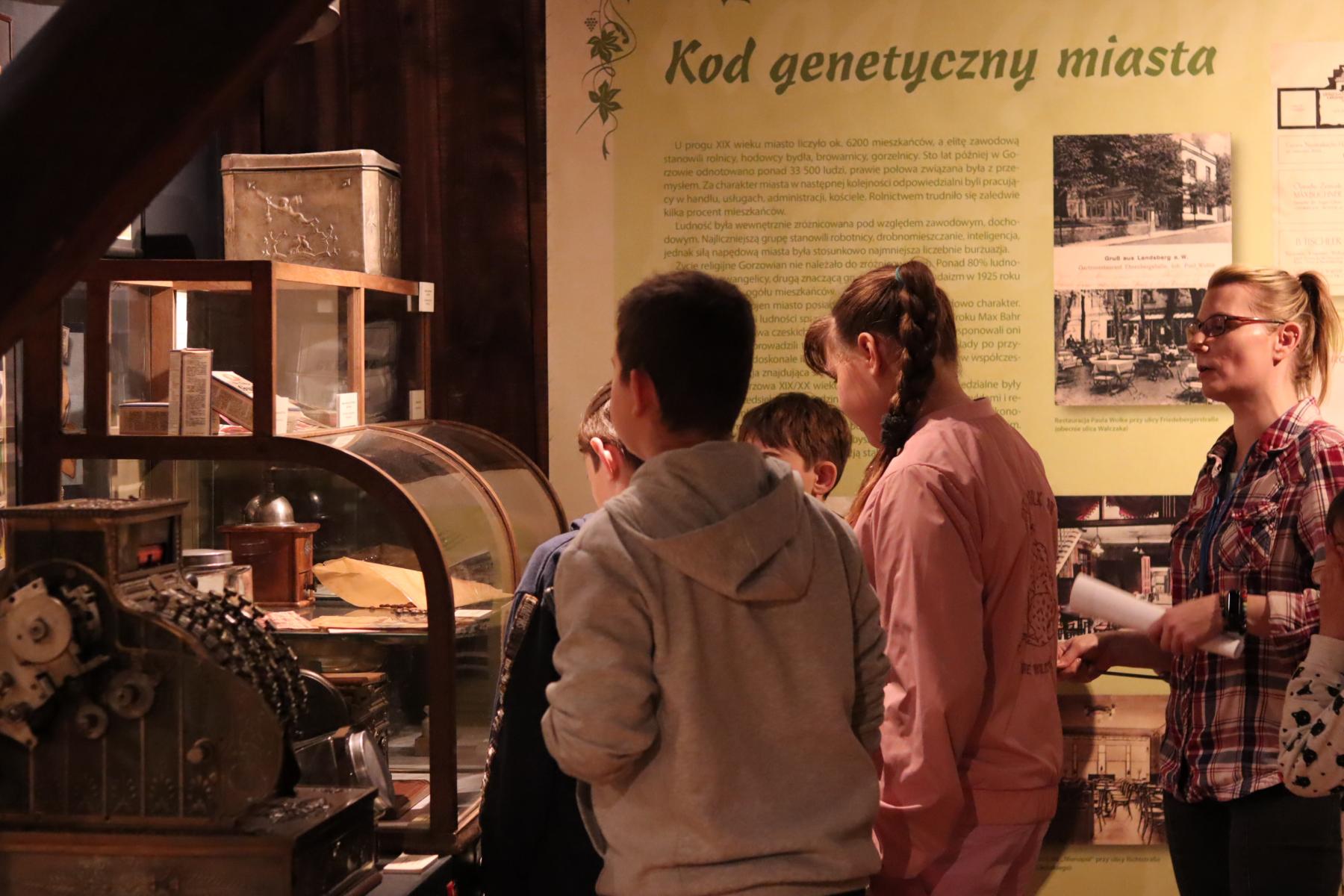 dzieci zwiedzają ekspozycję muzealną prezentującą wnętrze sklepu