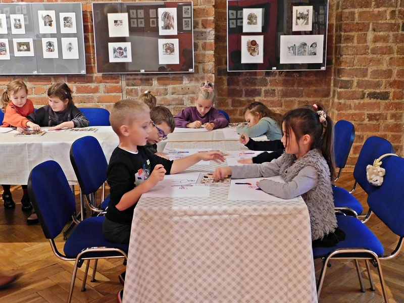 dzieci siedzą przy stolikach i rysują